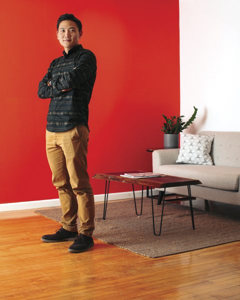 Gunhee Park standing with arms crossed in front of red wall