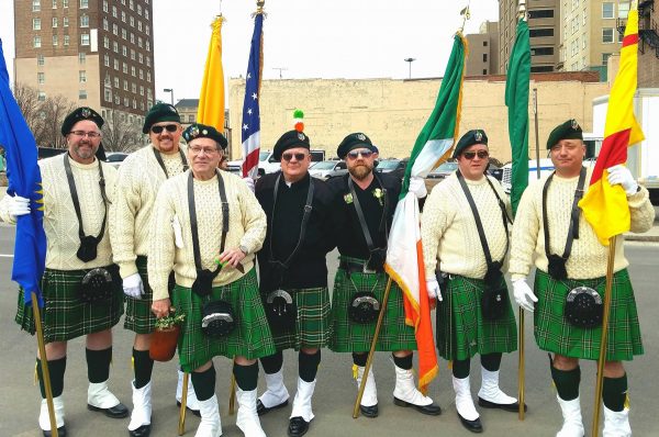 Seven men posing in kilts with flags, St. Patrick's Day Parade 