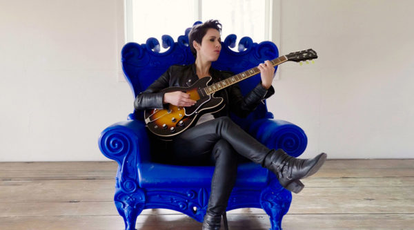 Gina Chavez, blue chair, with guitar