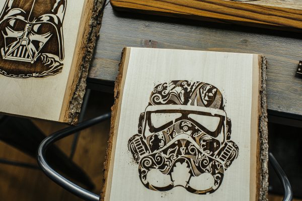 Two wood engravings, Darth Vader on left, storm trooper on right